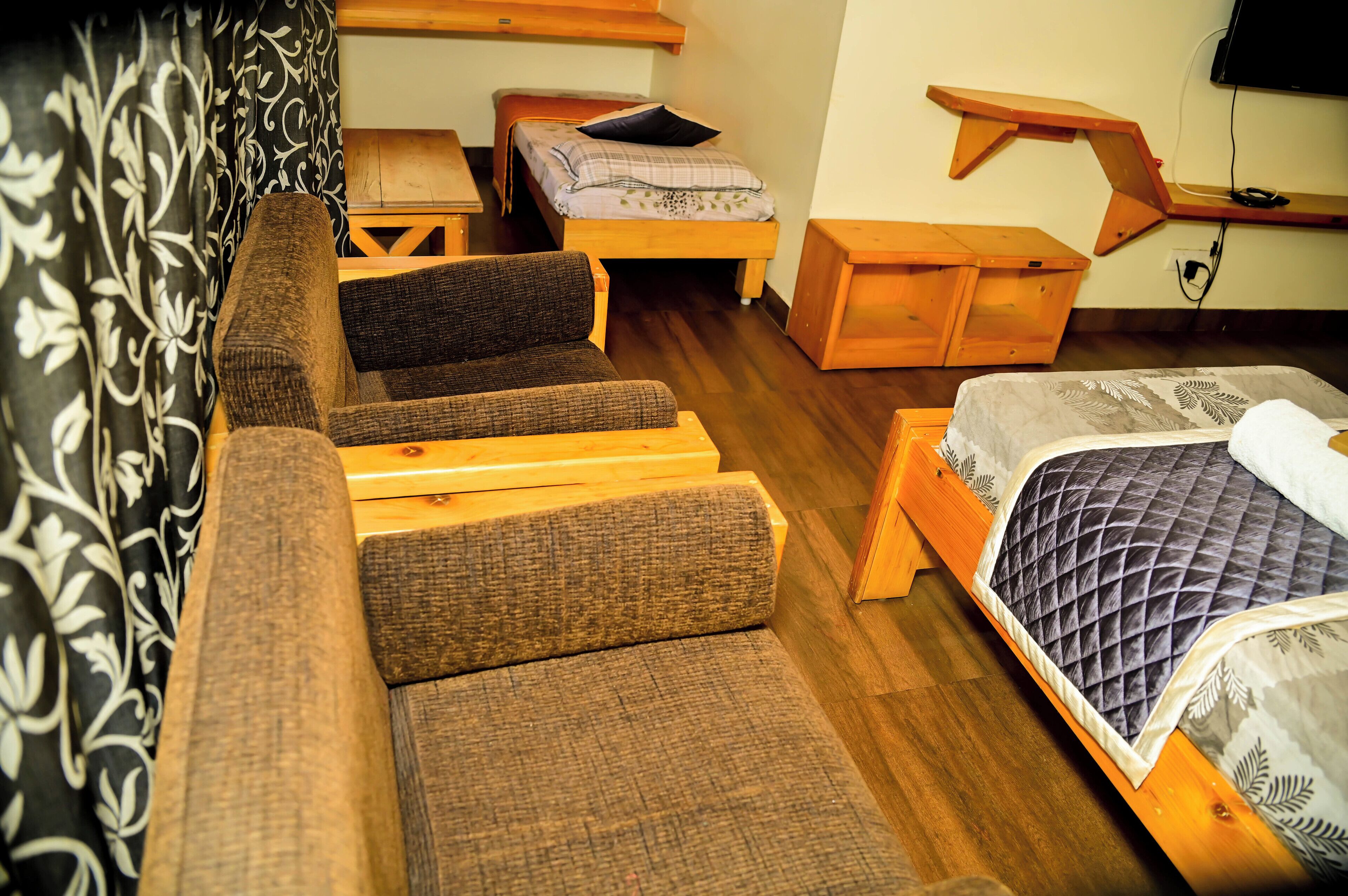Une pièce de taille modeste comprenant un lit, un canapé, une petite table et un banc en bois.