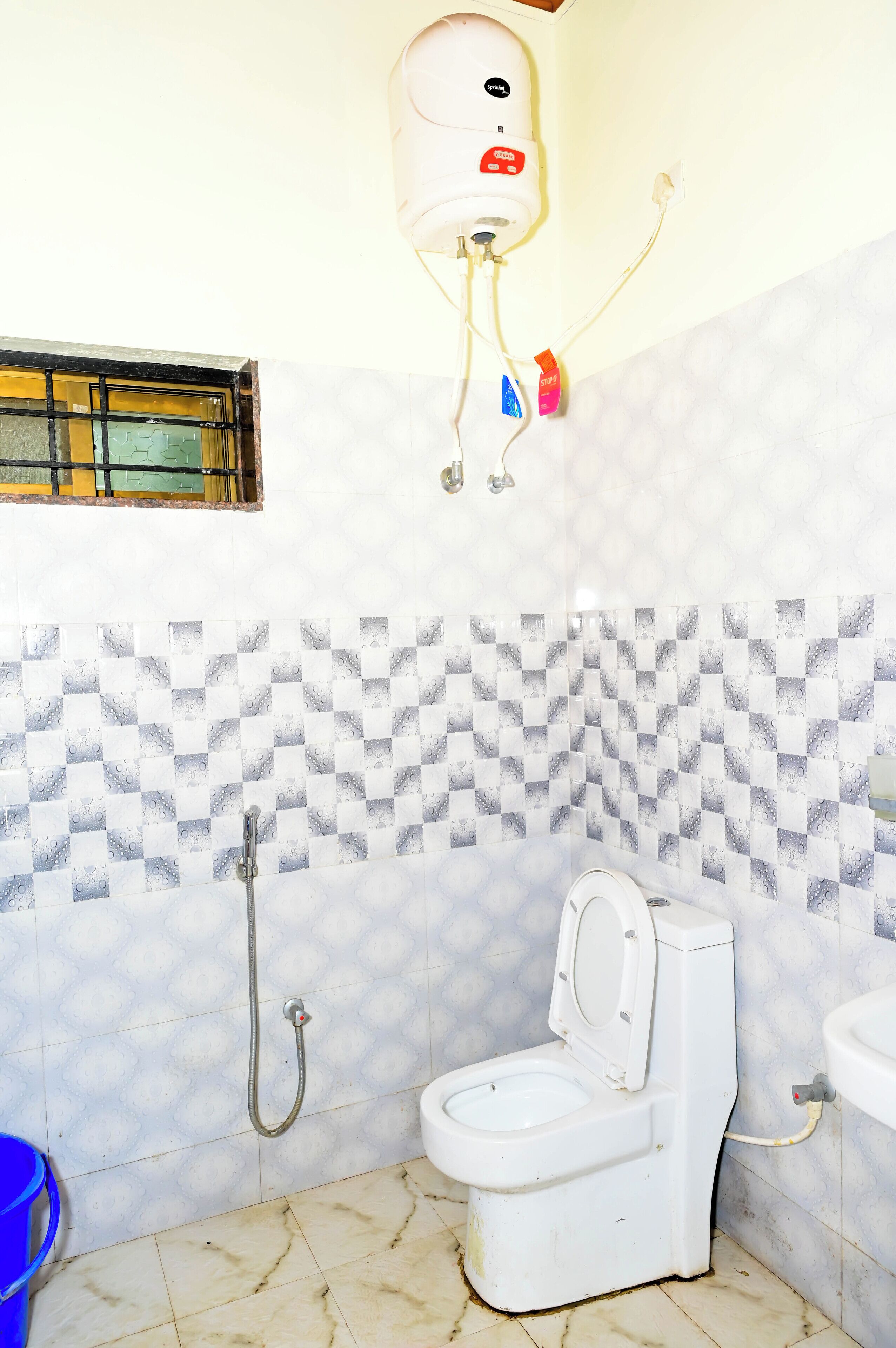 A bathroom with a toilet, a shower, and a hand dryer mounted on the wall.