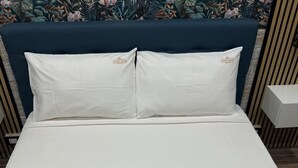 A neatly made bed with white linens and pillows, a headboard, and two towels with 'Luxury House Ballaro' branding. - Luxury house ballaro  (Palermo)
