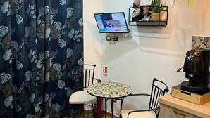 A small, cozy room with a round table, two chairs, a coffee machine, and a TV mounted on the wall. - Luxury house ballaro  (Palermo)