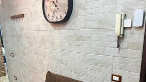 A brown leather sofa against a textured wall with a clock and a phone. - Luxury house ballaro  (Palermo)