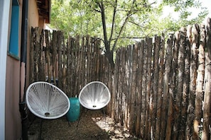A wooden fence, two white chairs, and a tree in a garden area. - Complejo de Closson- 4 Casitas- Railyard & Plaza (Santa Fe)