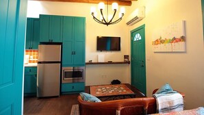 Una cocina compacta con armarios azul turquesa, un refrigerador, horno y un televisor sobre la encimera.
