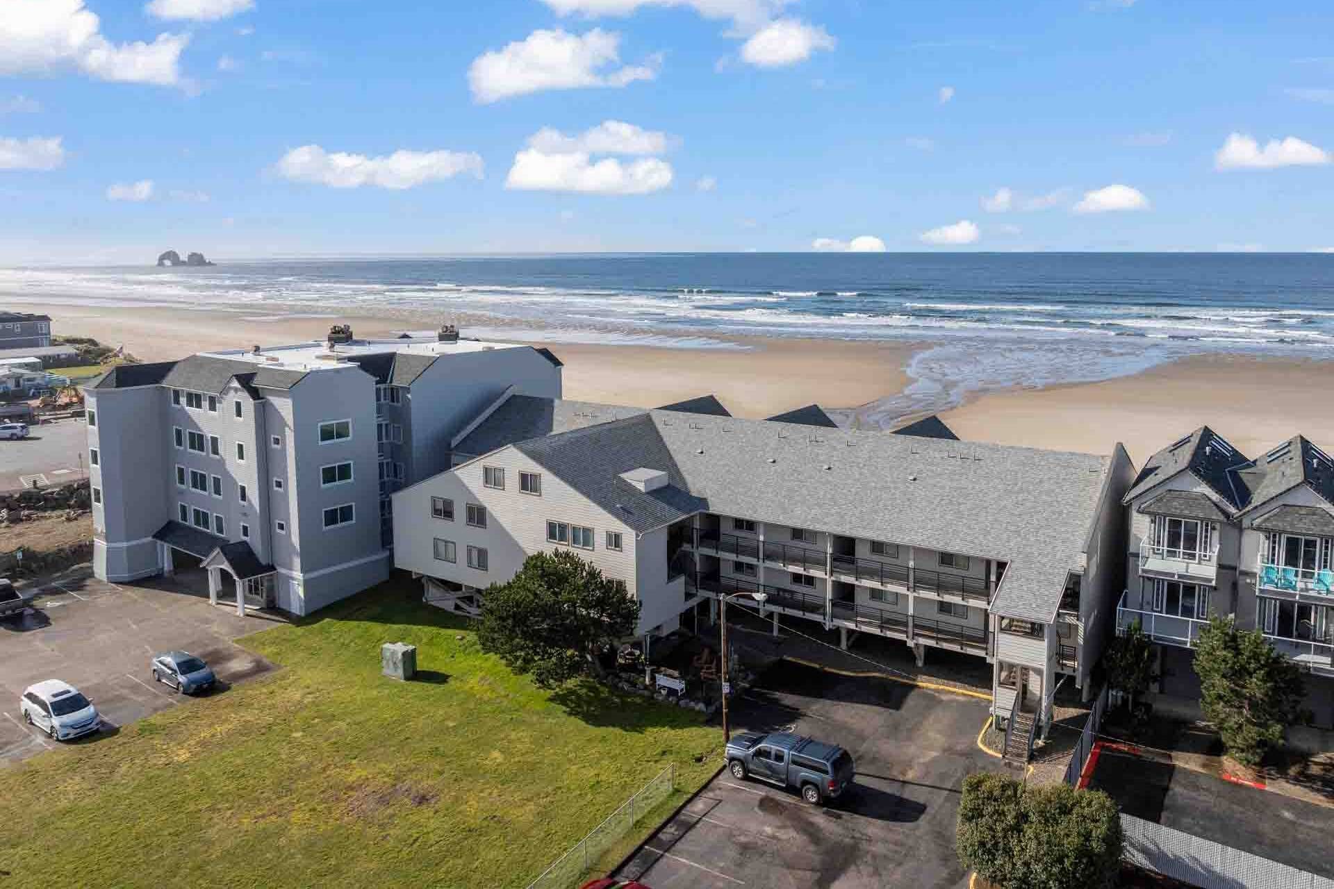 Un hotel de varios pisos con vista a la playa, zona de estacionamiento y un estacionamiento más pequeño.