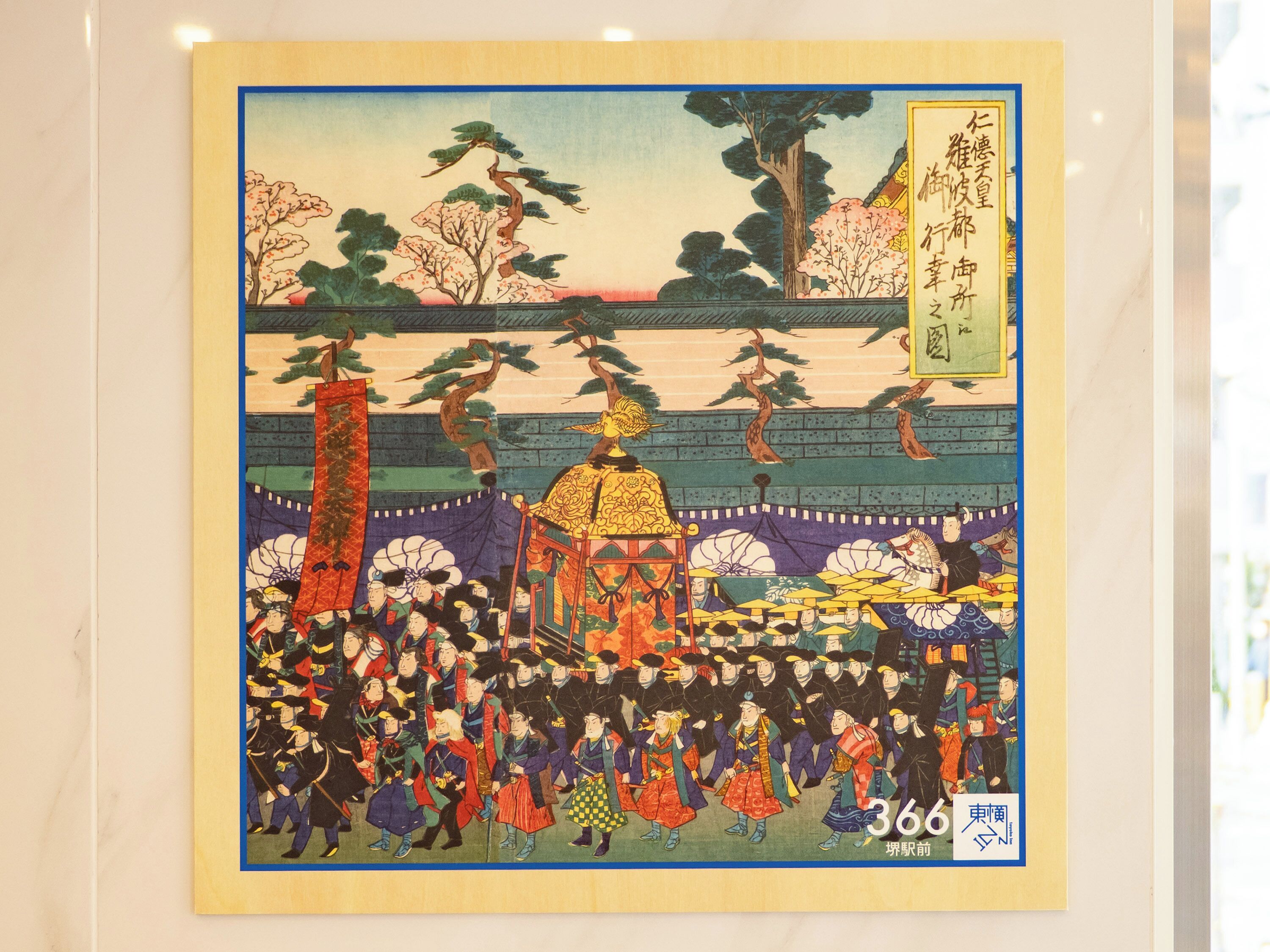 A framed artwork depicting a historical scene with figures in traditional attire, a prominent golden structure, and cherry blossoms.