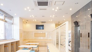 En modern restaurang med en lång bardisk, trästolar och en tv som är monterad på väggen.