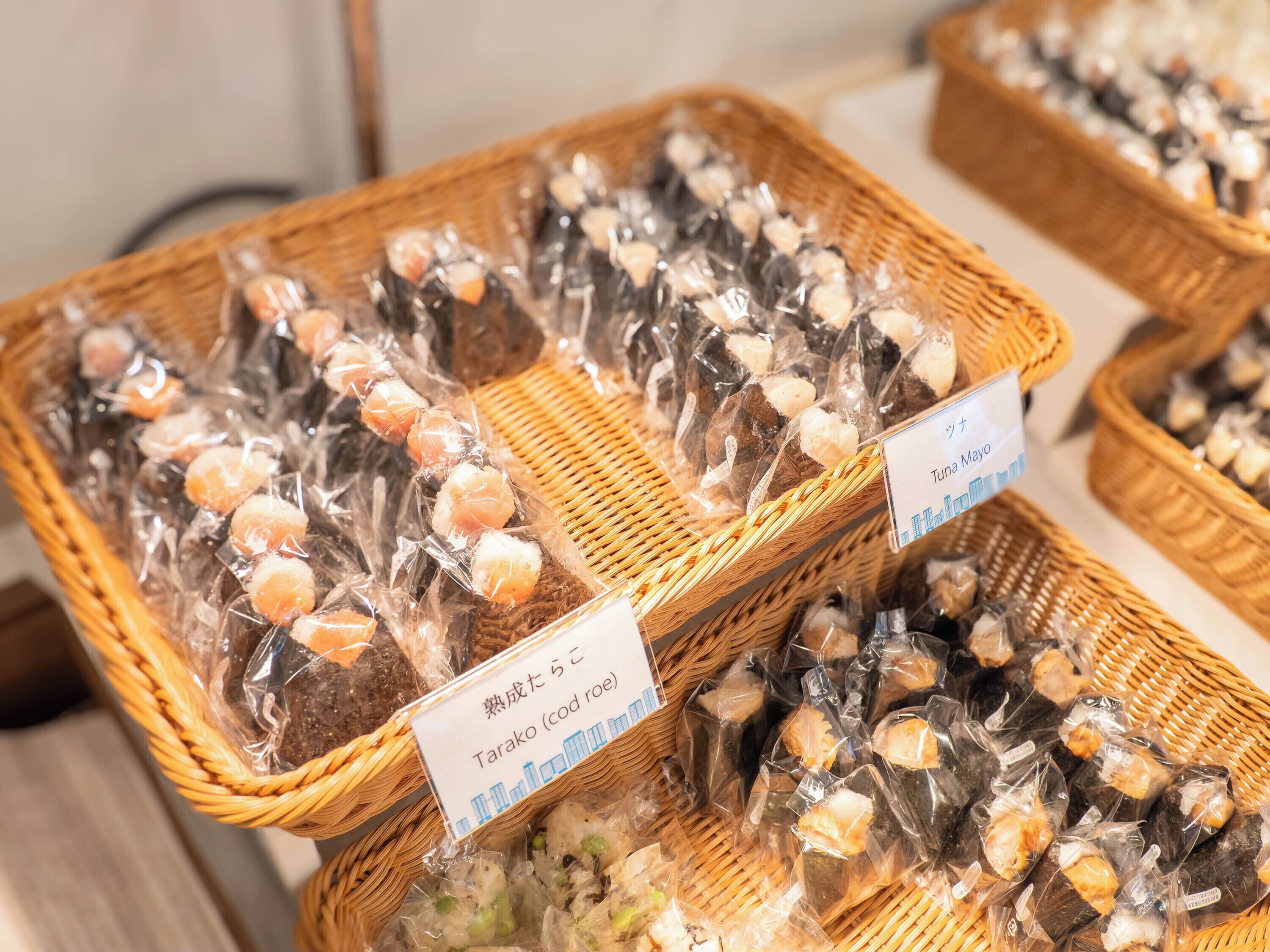 Baskets of packaged food items labeled "Tuna Mayo" and "Tarako (cod roe)" on a table.
