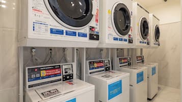 Une rangée de machines à laver à chargement frontal et de sèche-linge à pièces, dans un espace commercial.