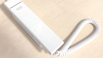 Un dispositivo electrónico blanco y rectangular con un cable enrollado sobre una superficie de madera.