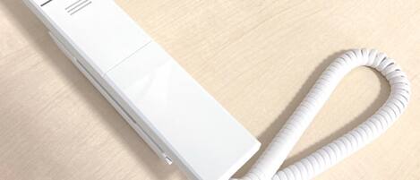 Un dispositivo electrónico blanco y rectangular con un cable enrollado sobre una superficie de madera.