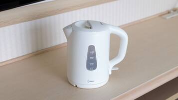 A white electric kettle with measurement markings on a wooden surface.
