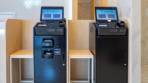 Dos quioscos de autoservicio con pantallas que muestran 'toyoko inn' en inglés y japonés, indicando un servicio de pago o registro.