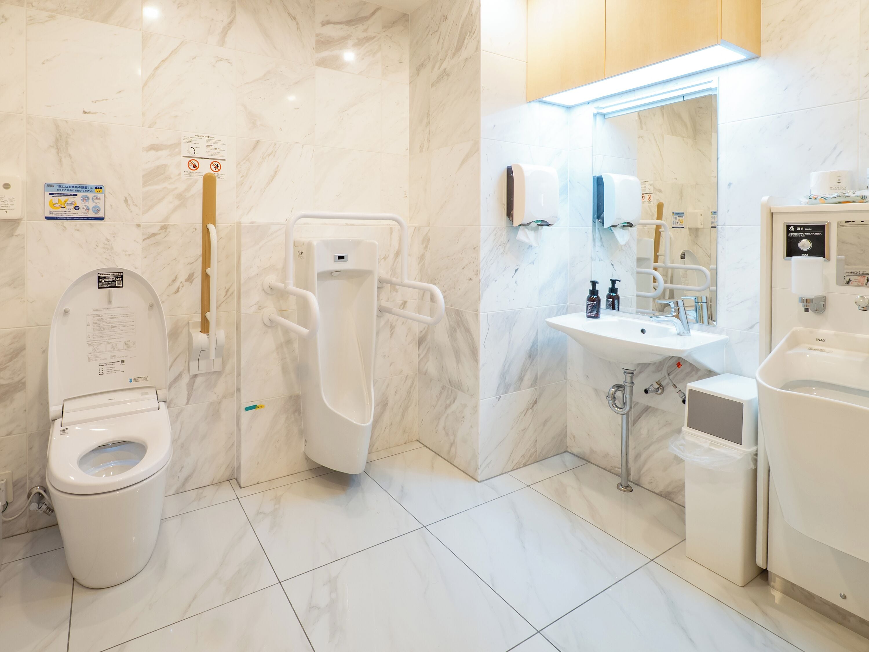 Un baño moderno con inodoro, orinal, lavamanos y bañera.