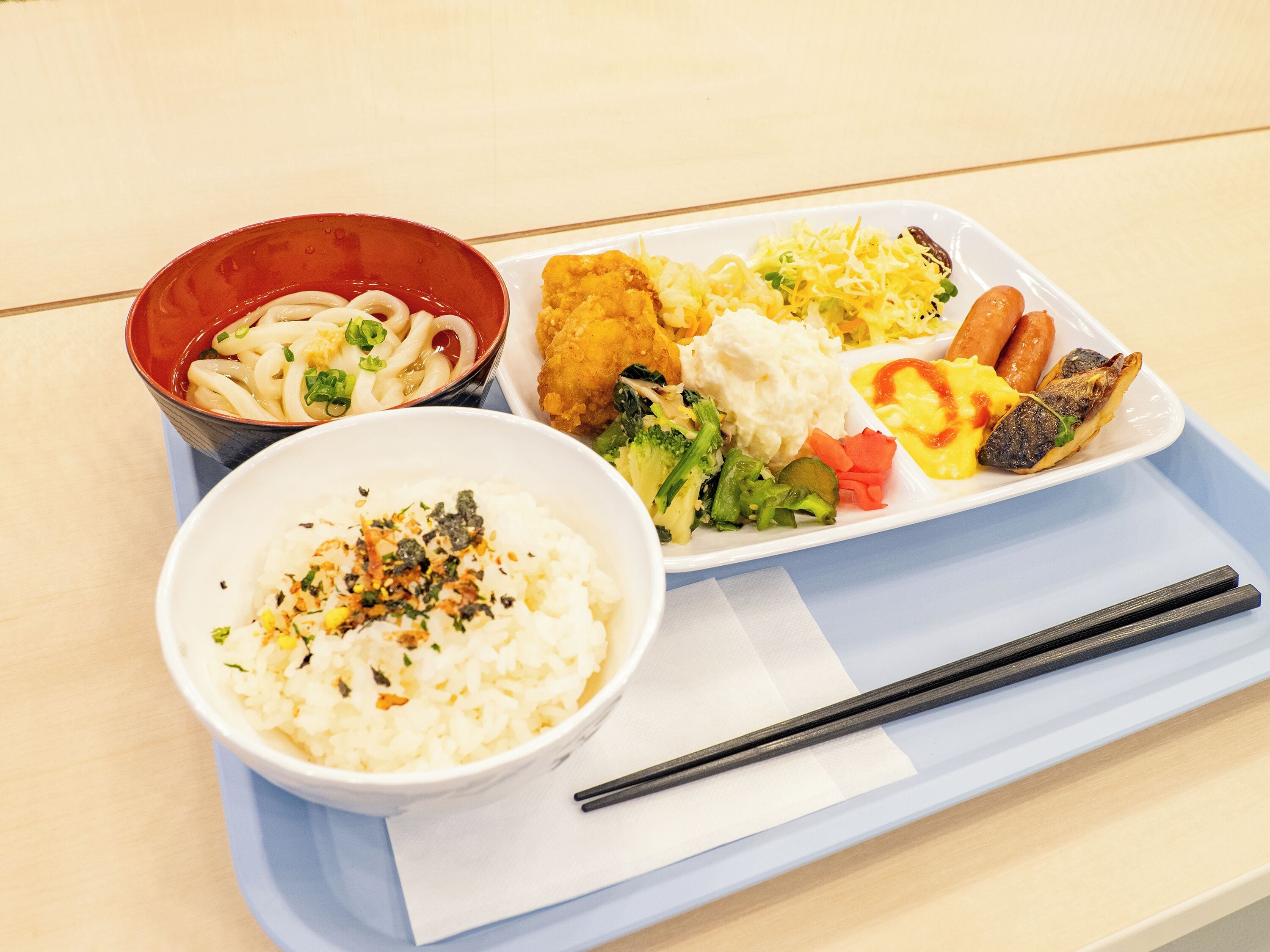 A tray with various dishes including noodles, fried items, and vegetables.