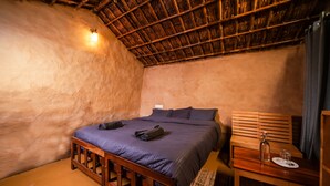 Una habitación acogedora con cama, banco de madera y una mesita con una botella y vasos.