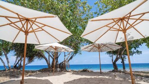 A beach with white umbrellas and wooden poles, trees, and the ocean in the background. - Sofanda Resort (Nangamiro)