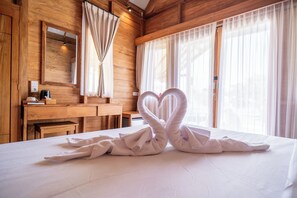 Ein Hotelzimmer mit Holzwänden, einem großen Bett, einem Holztisch und einem Spiegel.