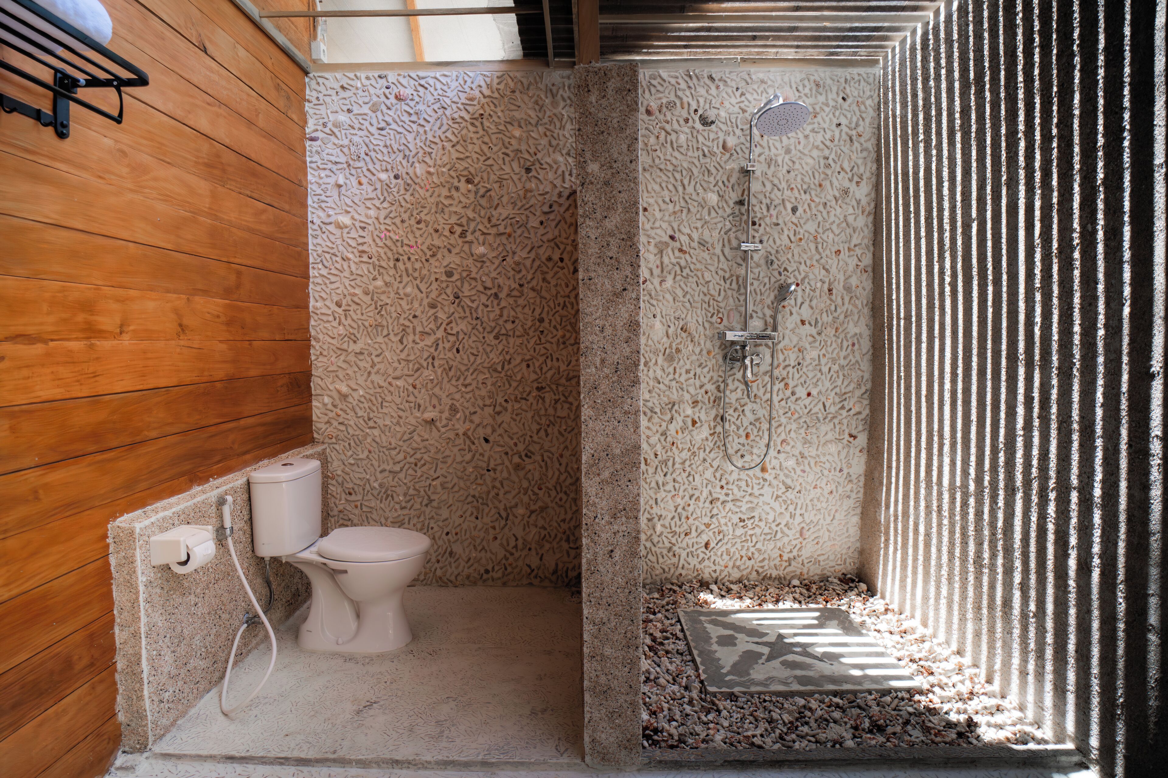 A small, enclosed bathroom with a toilet, shower, and a wooden wall.