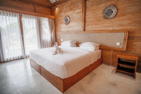 A wooden-framed bedroom with a large bed, two wall-mounted clocks, and a small wooden nightstand. - Sofanda Resort (Nangamiro)