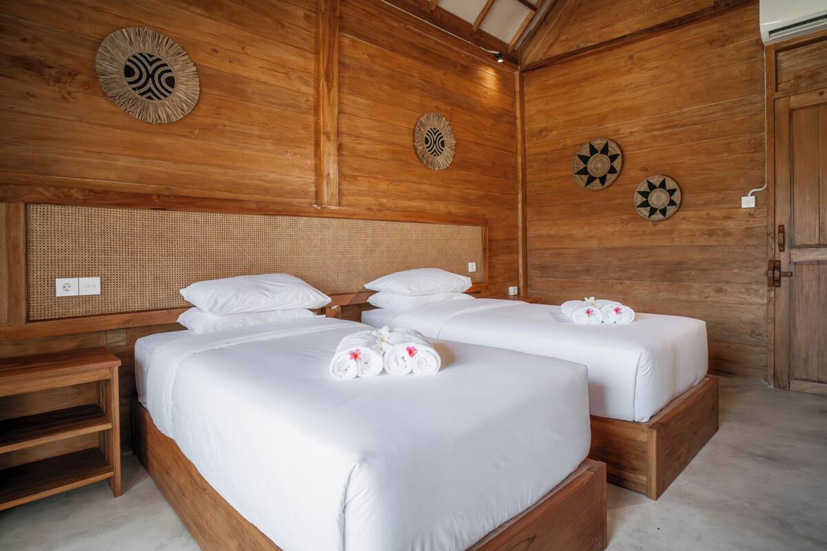 A wooden room with two beds, a woven headboard, and decorative wall art.