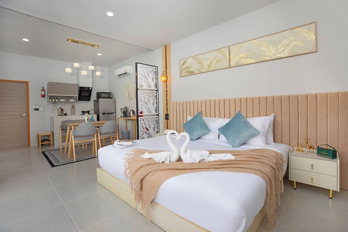 A modern hotel room with a large bed, a bedside table, a nightstand, a desk, and a chair.