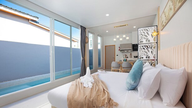 Ein modernes Hotelzimmer mit einem großen Bett, Meerblick, einer Küchenzeile und einem Balkon.