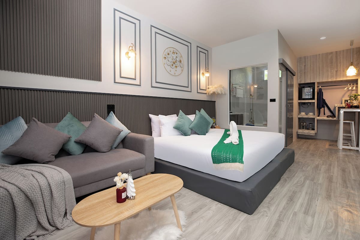 A modern hotel room with a large bed, a sofa, a small table, and a TV.