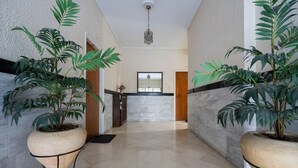 Passadís amb plantes en testos a banda i banda, una taquilla d'hostes i un paviment de marbre.