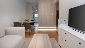 Un saló modern amb un sofà, un televisió de pantalla plana i una zona menjador amb cadires i una taula.