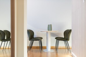 A dining area with a white table and four green chairs.