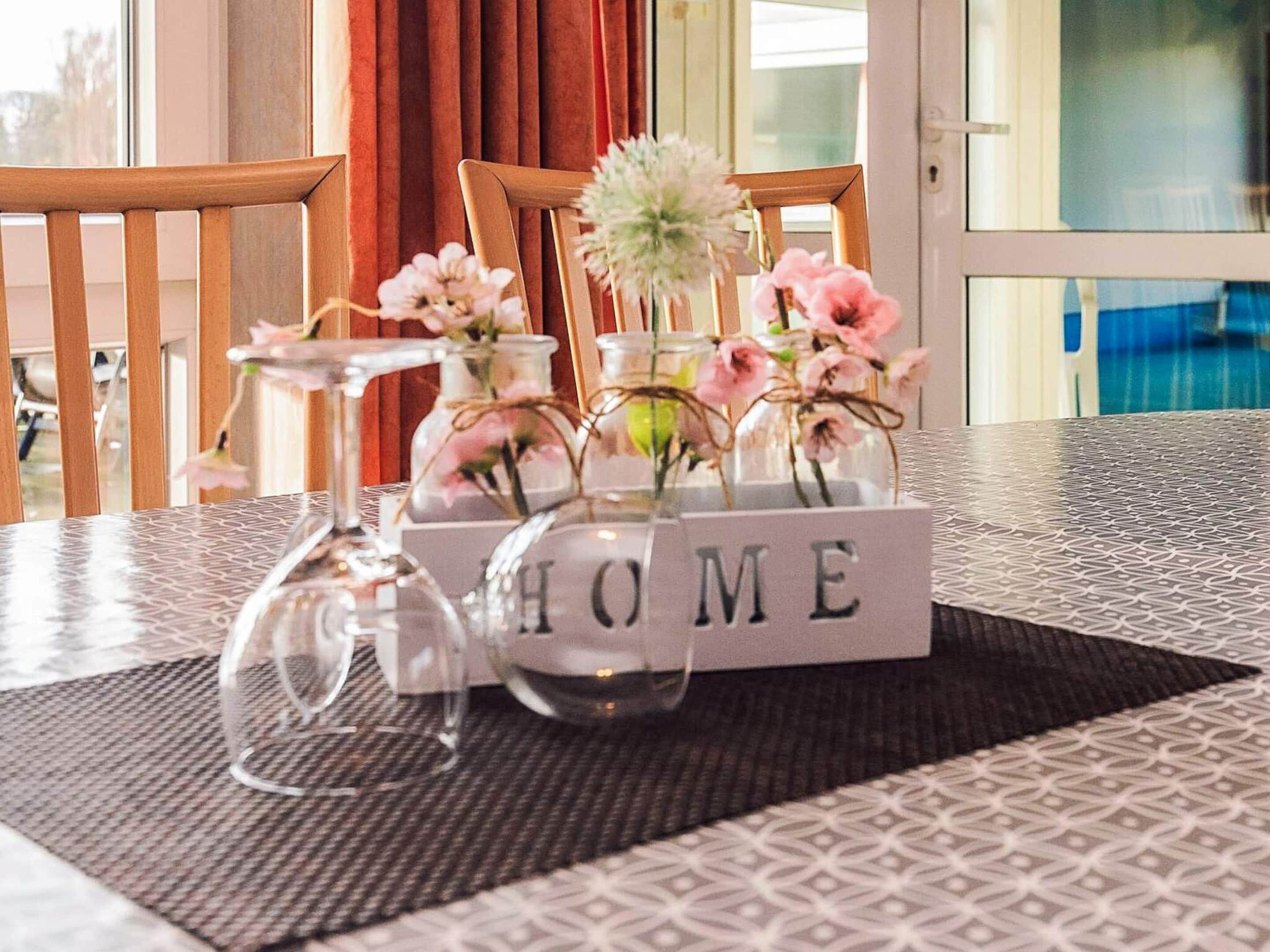 Una mesa con un florero decorativo, un recipiente de vidrio y un cartel que dice "HOME".