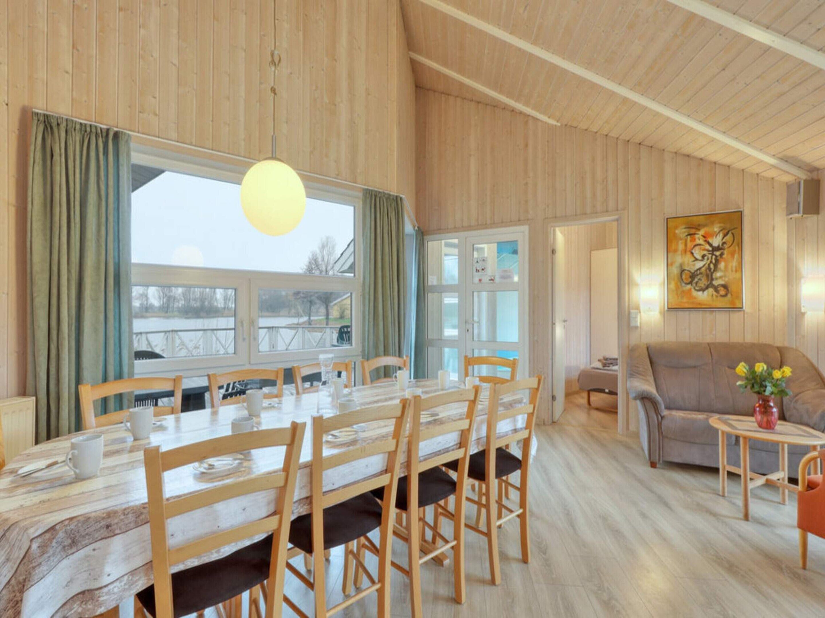 Ein geräumiger Raum mit einem Holzespeisesaal und Stühlen, einem Sofa und einem Gemälde an der Wand.