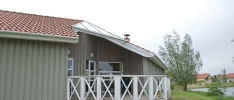 Ein einstöckiges Gebäude mit rotem Ziegeldach, einer weißen Veranda mit Querstreben und einem kleinen Fenster.