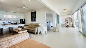 A spacious living area with a sofa, coffee table, and decorative items. A kitchen is visible in the background with modern appliances.