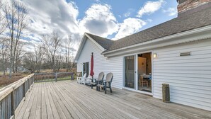 En træterrasse med udendørs møbler, et overdækket område og en bygning med en skydedør.