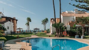 A swimming pool with a clear view of the ocean, surrounded by palm trees and a building with a tiled roof. - Creta sunset by BH Marbella (Marbella)