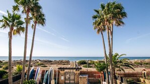 A beach view with palm trees, a gate, and surfboards. - Creta sunset by BH Marbella (Marbella)