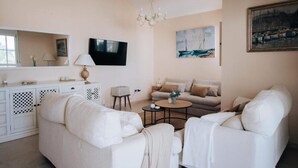 A modern living room with white furniture, a television, a chandelier, and artwork on the walls. - Creta sunset by BH Marbella (Marbella)