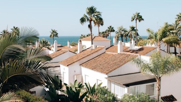 A coastal residential area with white buildings, palm trees, and a view of the sea. - Creta sunset by BH Marbella (Marbella)