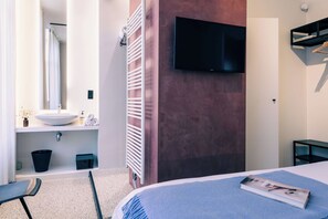 A modern hotel room with a large bed, a mounted TV, a built-in sink, and a towel rack. - Ghent Getaway: Cozy Retreat for Two (Gent)