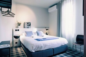 A hotel room with a large bed, a bedside table, a chair, and a wall-mounted air conditioner. - Ghent Getaway: Cozy Retreat for Two (Gent)