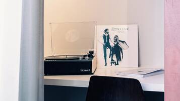 A desk with a vinyl record player, a framed album cover, and a book titled "A Modern Way to Live".