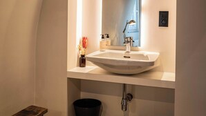 Et moderne badeværelse med en hvid vask, et spejl og en lille skammel.