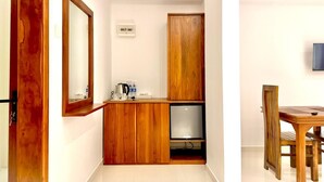 A compact room with a wooden cabinet, a small TV, and a dining table with chairs. - Easy Stay (Kandy)