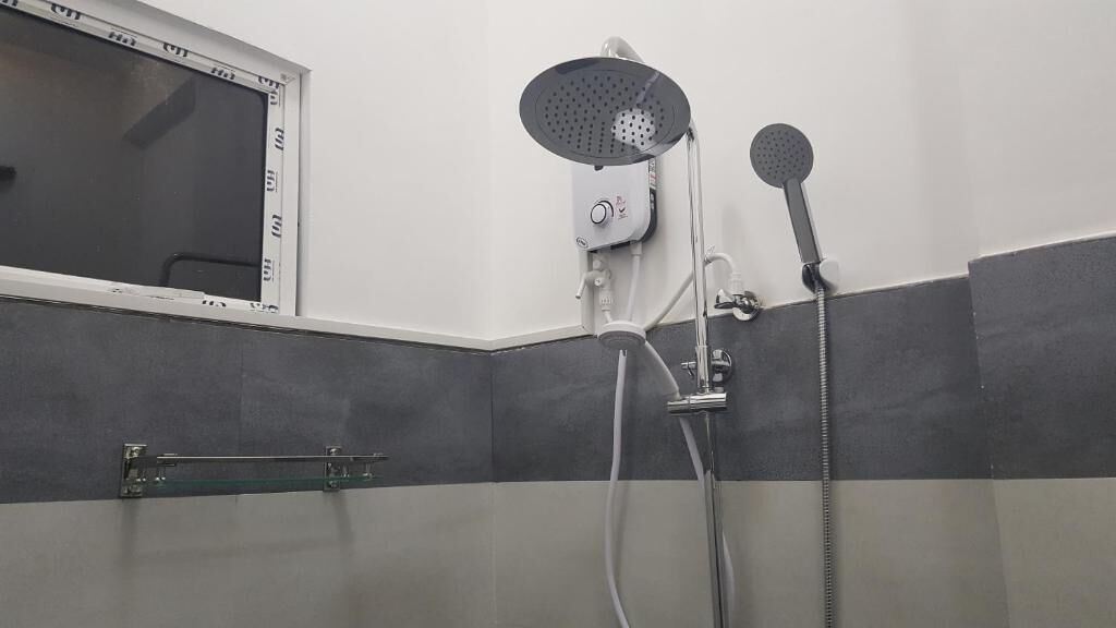 A shower with a handheld showerhead and a wall-mounted showerhead, a window with a metal frame, and a glass shower door.