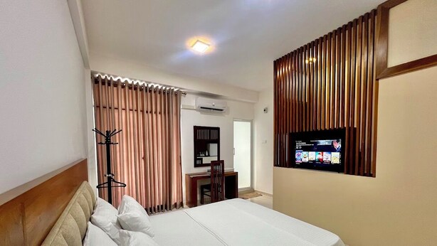 A hotel room with a bed, a desk, a television, and a wardrobe. - Easy Stay (Kandy)
