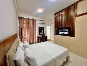 Ein Hotelzimmer mit Bett, Schreibtisch, Fernseher und Kleiderschrank.