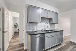 Una cocina moderna con armarios grises, encimera negra y lavavajillas de acero inoxidable.
