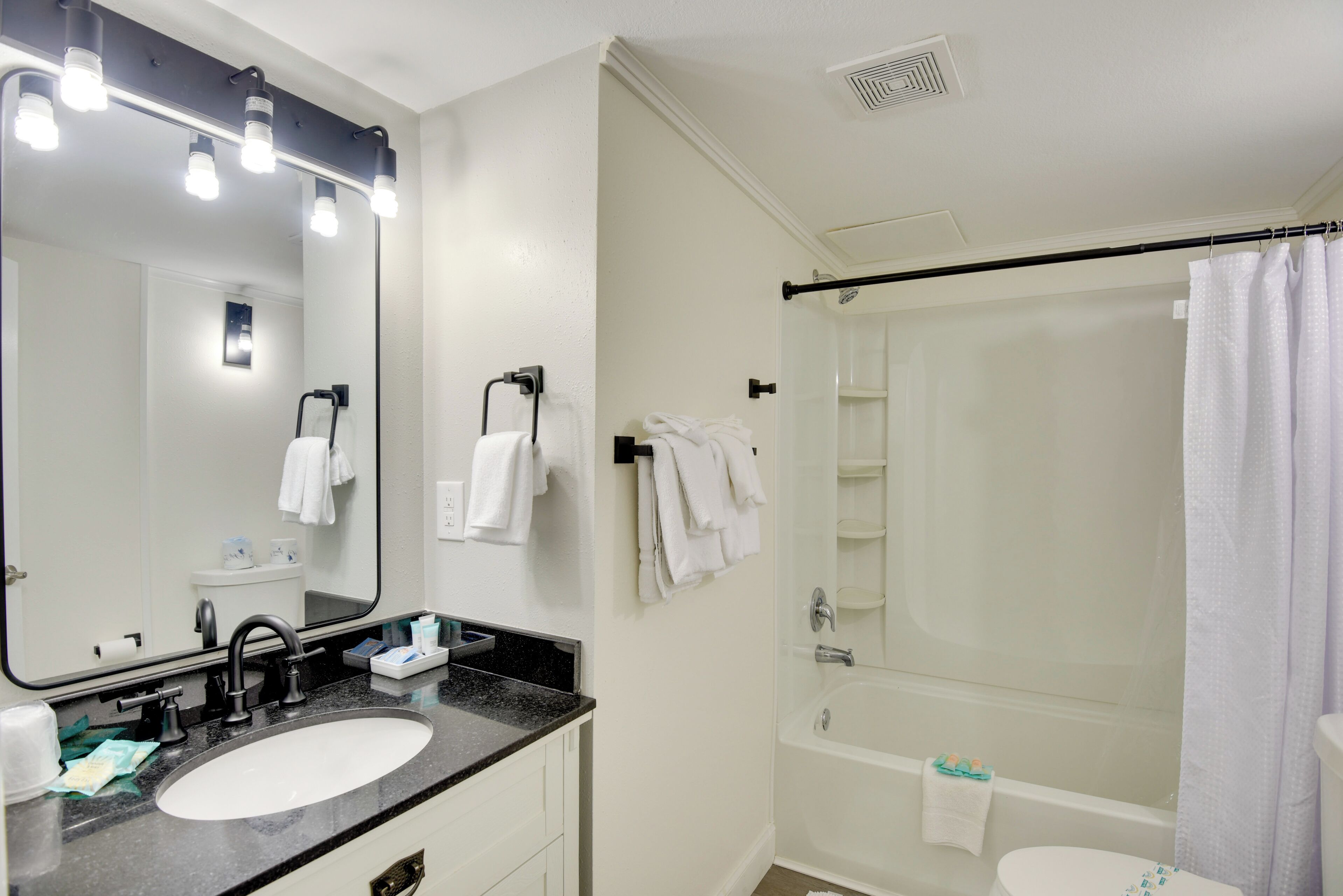 Un baño con un espejo grande, lavamanos y bañera.