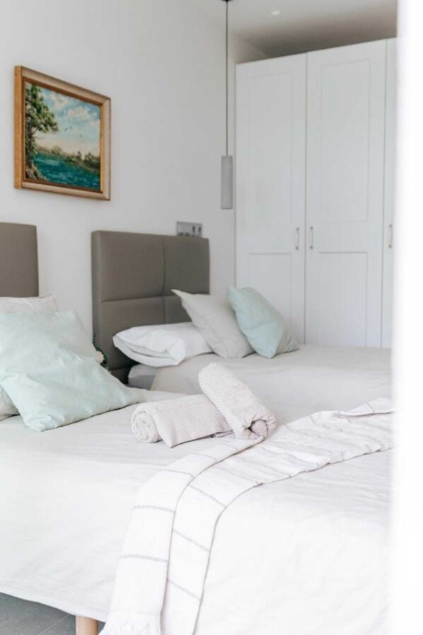 A bedroom with a bed, pillows, a headboard, a wardrobe, and a painting on the wall.
